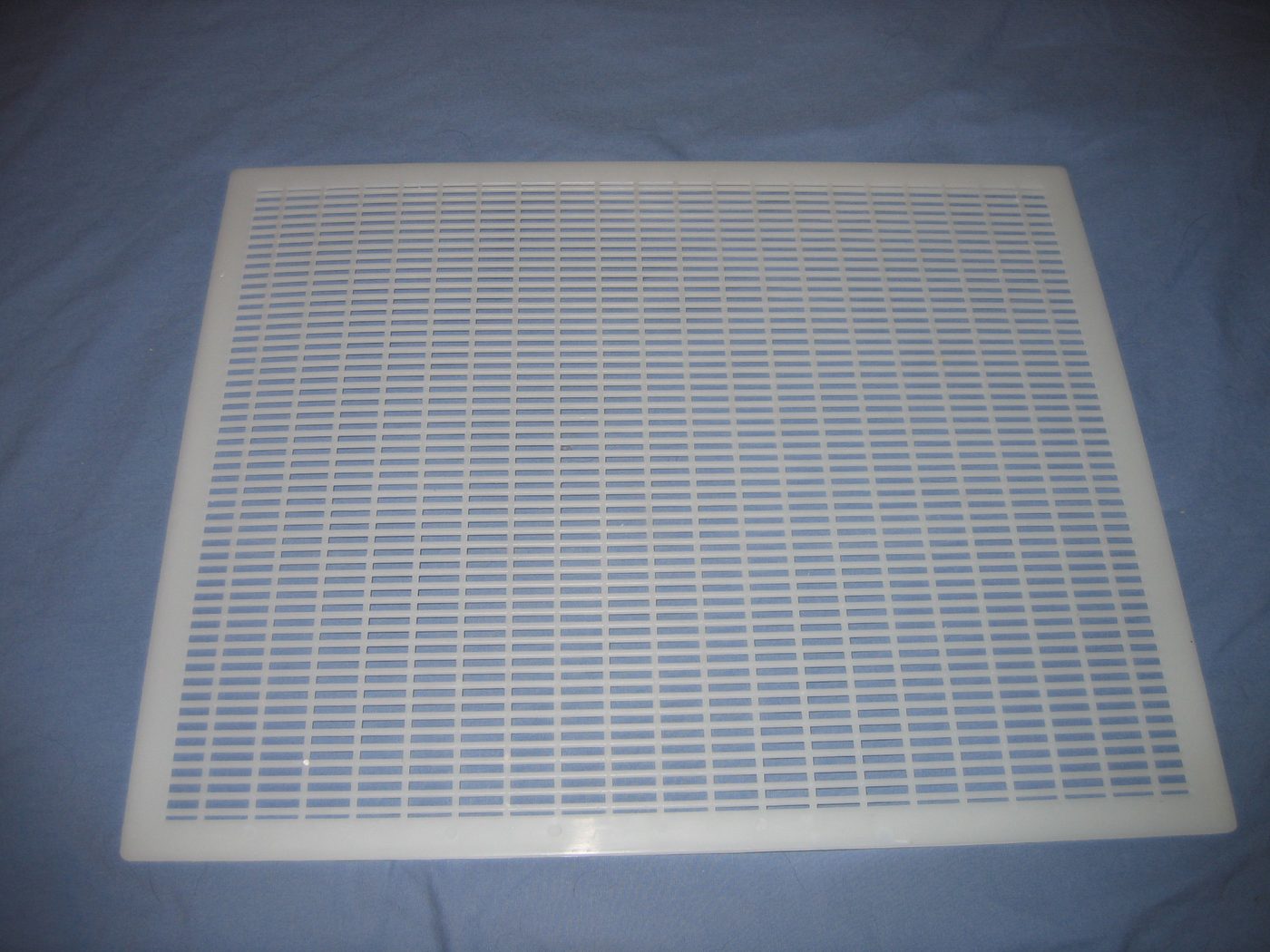 A plastic queen excluder, a grid used in a beehive.